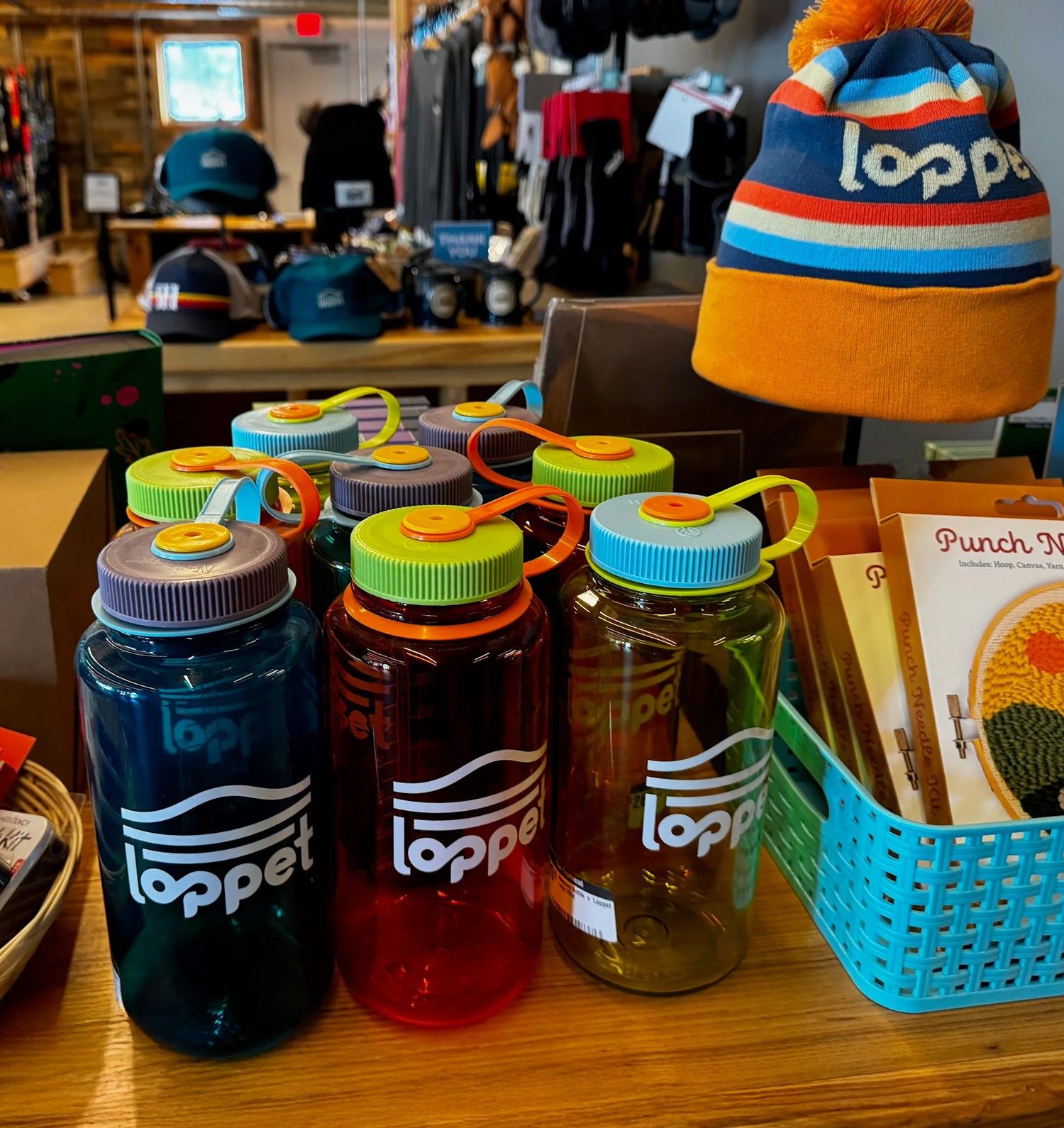 Set of Lopper water bottles on a table with a colorful beanie in the background.