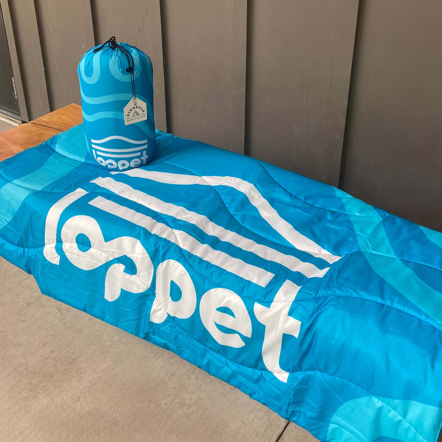 Blue camping blanket with 'loppet' branding on a wooden surface.